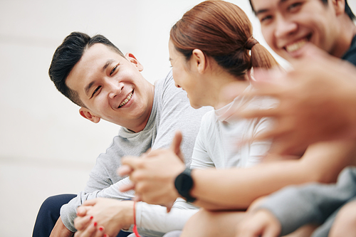 Handsome positive young Vietnamese man talking to his friends after sports training