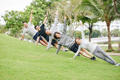 Group of positive fit young Asian people standing in side plank on slope on university campus