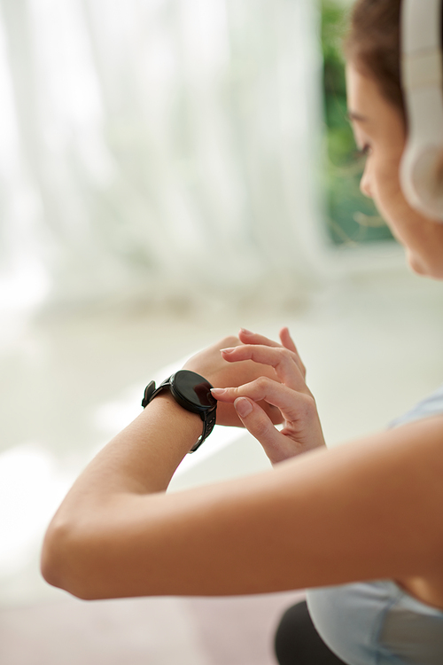 Young woman checking smartwatch after working out at home