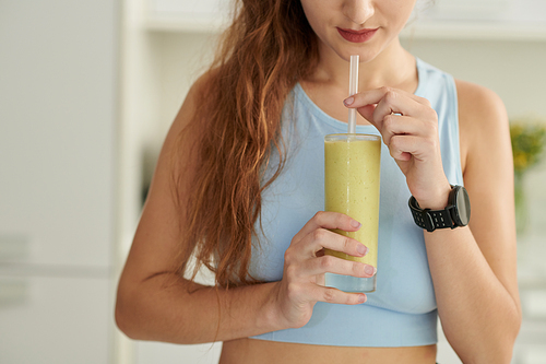 Cropped image of young woman drinking healthy fruit smoothie for breakfast