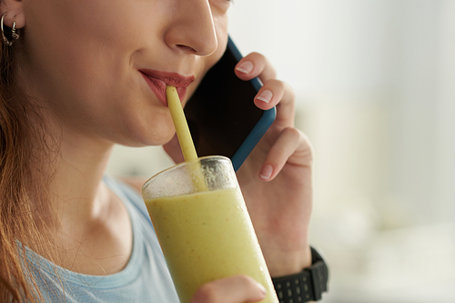 Woman sipping smoothie and talking on phone