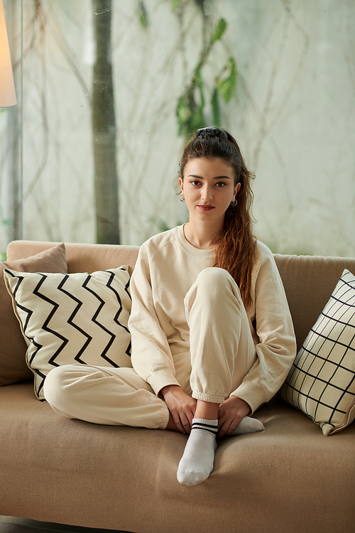 Young woman in comfy loungewear resting on sofa at home