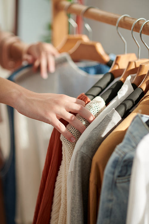 Cropped image of woman choosing clothes in closet when deciding what to wear