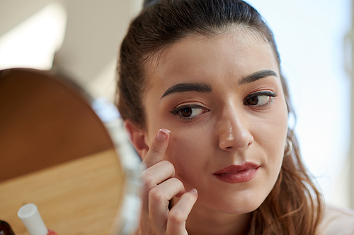Closeup image of young woman applying brightening eye cream