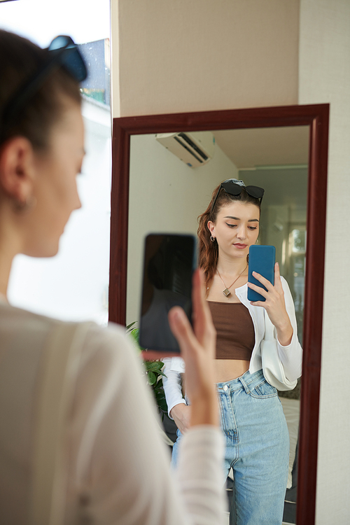 Girl taking selfie in big mirror to upload on social media