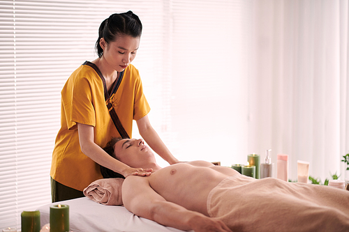 Young man getting relaxing chest, neck and shoulders massage in spa salon