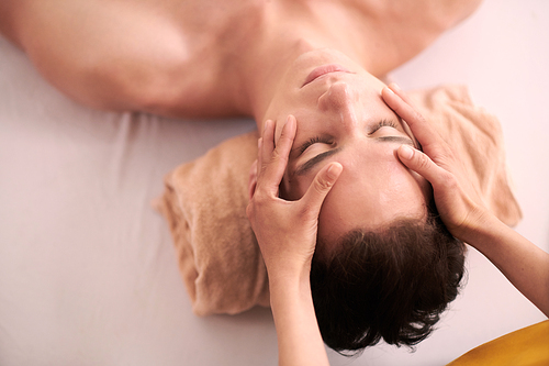 Beautician giving man relaxing and rejuvenating face massage