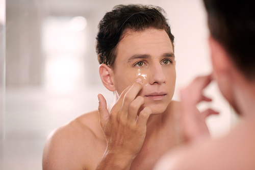 Man looking at bathroom mirror when applying silicone undereye patches