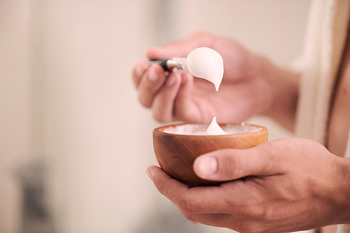 Closeup image of man applying revitalizing and nourishing face mask