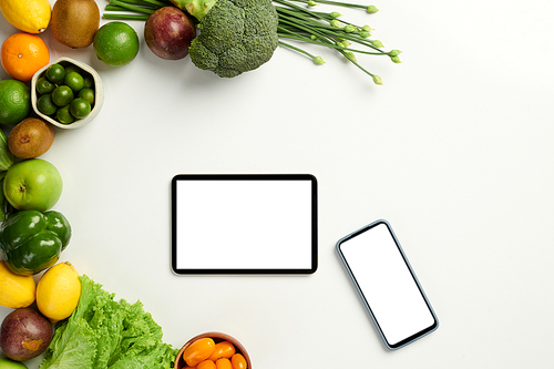 Various gadgets on table with fresh groceries, food delivery concept
