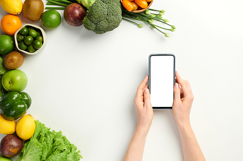 Hands of vegan ordering local fruits and vegetables via mobile application