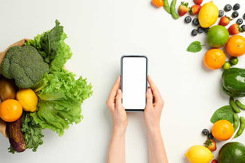 Hands of person using mobile app to find smoothie recipe to make from organic fruits and vegetables
