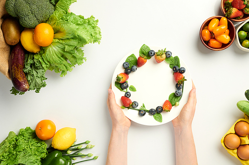 Person putting plate with fresh berries on table, health eating concept