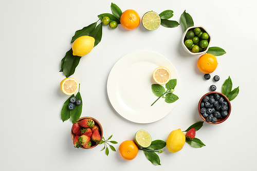 Berries and citrus fruits around plate with slice of lemon