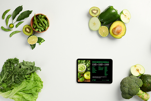 Green smoothie recipe on tablet next to fresh ingredients