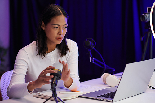 Young Asian woman setting microphone sound when getting ready to record podcast