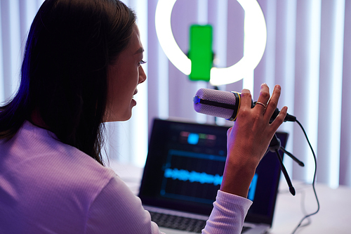 Blogger speaking in professional microphone when recording podcast for her blog