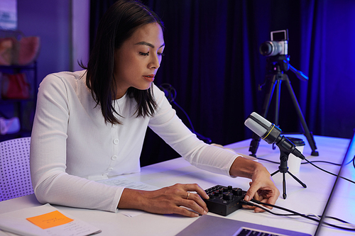 Blogger putting microphone cord in amplifier to get better sound for her podcast