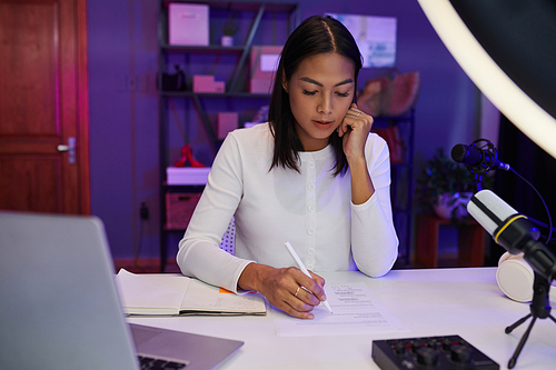 Influencer checking script and writing down jokes for her blog or podcast