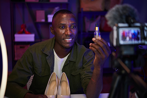 Smiling Black man filing review of face serum for his beauty blog