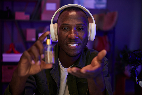 Smiling Black man filming blog on male skincare and recommending beauty products