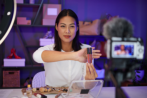 Beauty blogger filming makeup with warm lipstics