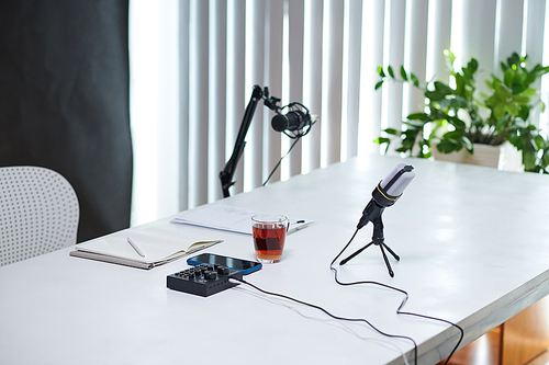 Microphone, cup of tea, planner and amplifier on table in studio