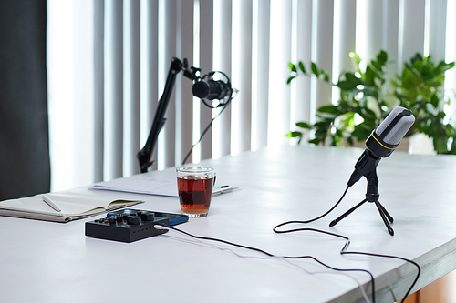 Microphones, amplifier and cup of black tea on table ready for recording podcast