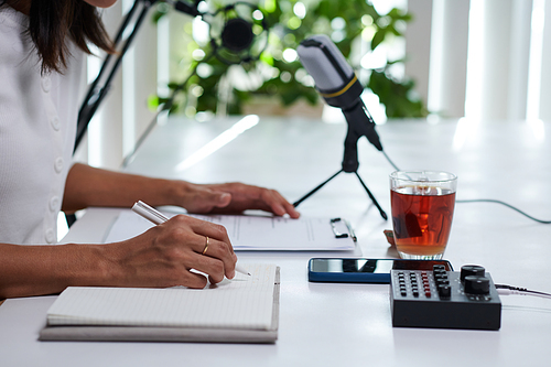 Blogger checking script and taking notes when recording podcast with guest