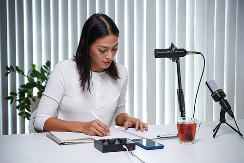 Creative woman working on scenario for new podcast at tablet in her studio