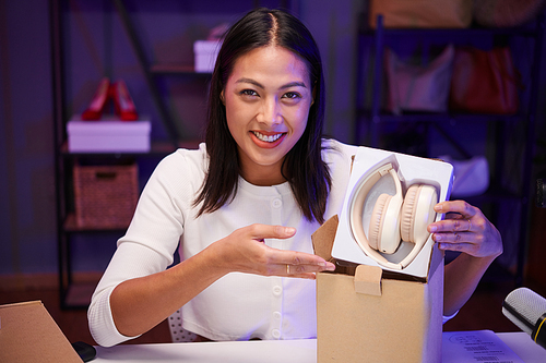 Joyful blogger filming review of new headphones for her blog