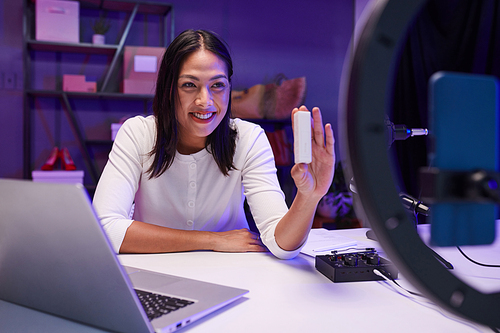 Joyful young woman filming review of new small device for blog