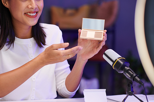 Cropped image of cheerful beauty blogger showing new contour palette to her subscribers