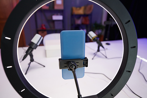 Smartphone attached to ring light in studio of beauty blogger