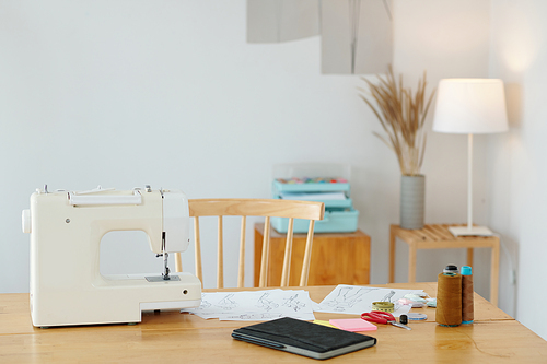 Desk of fashion designer with sewing machines and sketches for new collection