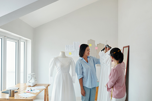 Tailor showing finished wedding dress to client