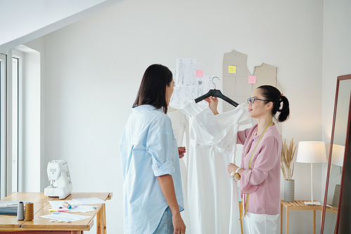 Seamstress showing finished wedding dress to customer