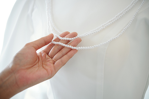 Woman touching peral necklace on mannequin with wedding dress