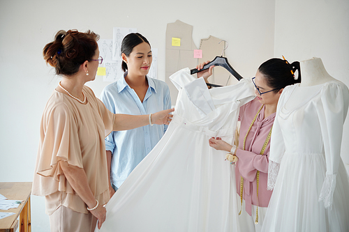 Mother helping daughter to find best wedding dress in store