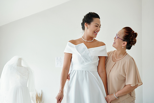 Senior woman hugging excited daughter in wedding dress