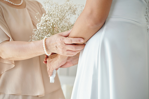 Mother touching hand of bride to support her on wedding day