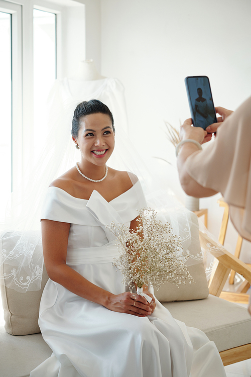 Happy elegant bride asking mother to photograph her on wedding day