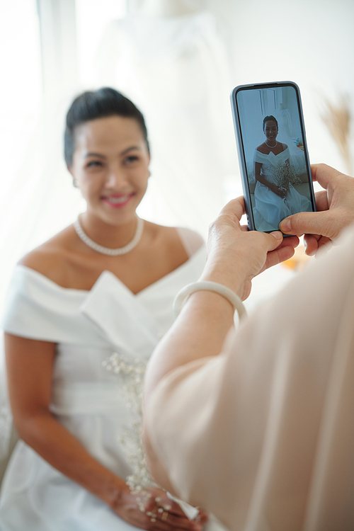 Mother photographing daughter in wedding dress