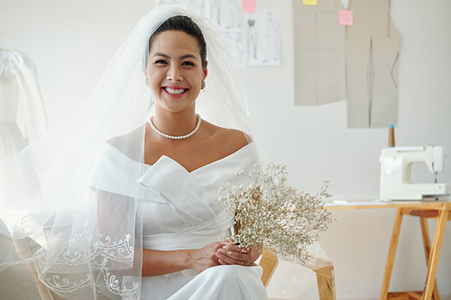 Portrait of happy smiling bride in wedding dress holding flowers