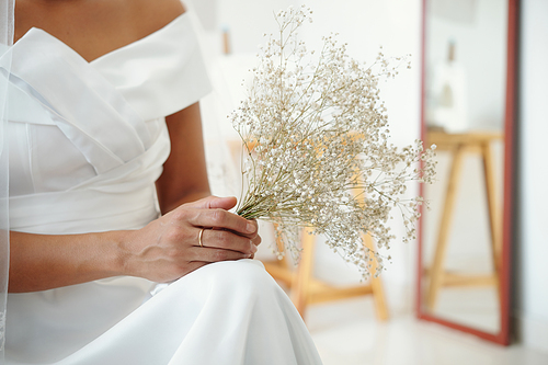 Small bouquet in hands of bride in white dress