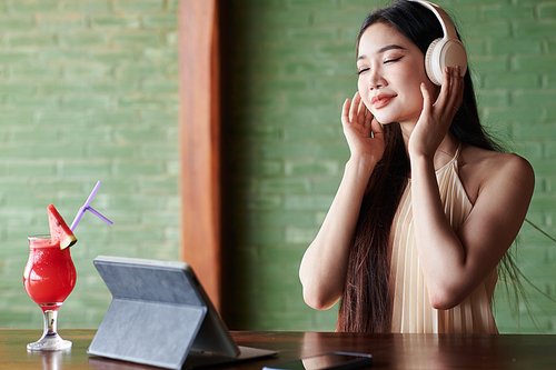 Smiling young woman enjoying good music in headphones