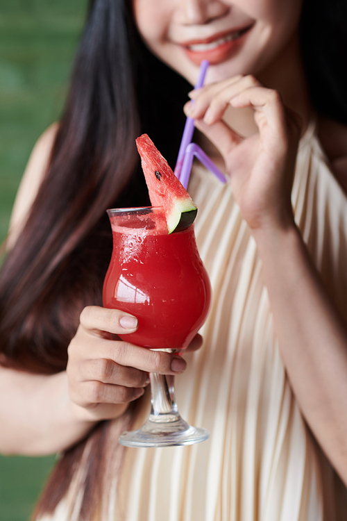 Cropped image of young woman sipping refreshing watermelon cocktail