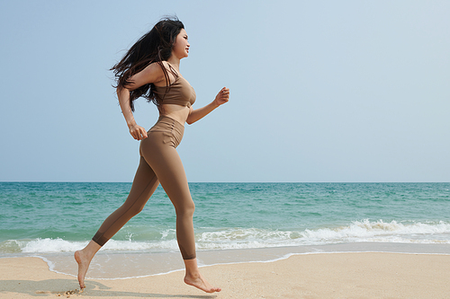 Fit young woman jogging on beach in the morning