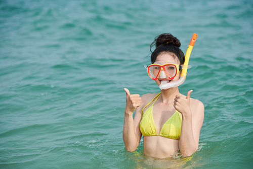 Portrait of smiling young woman in yellow biking diving in sea