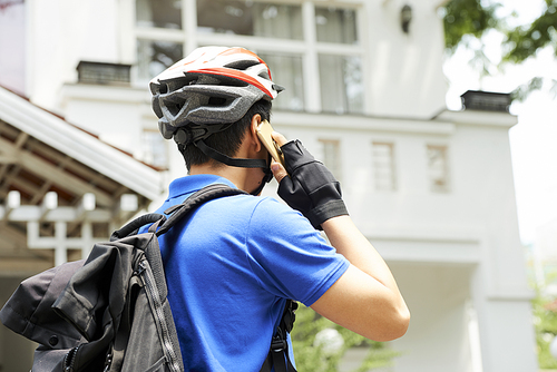 Delivery man in bicycle helmet calling customer and asking to open the door